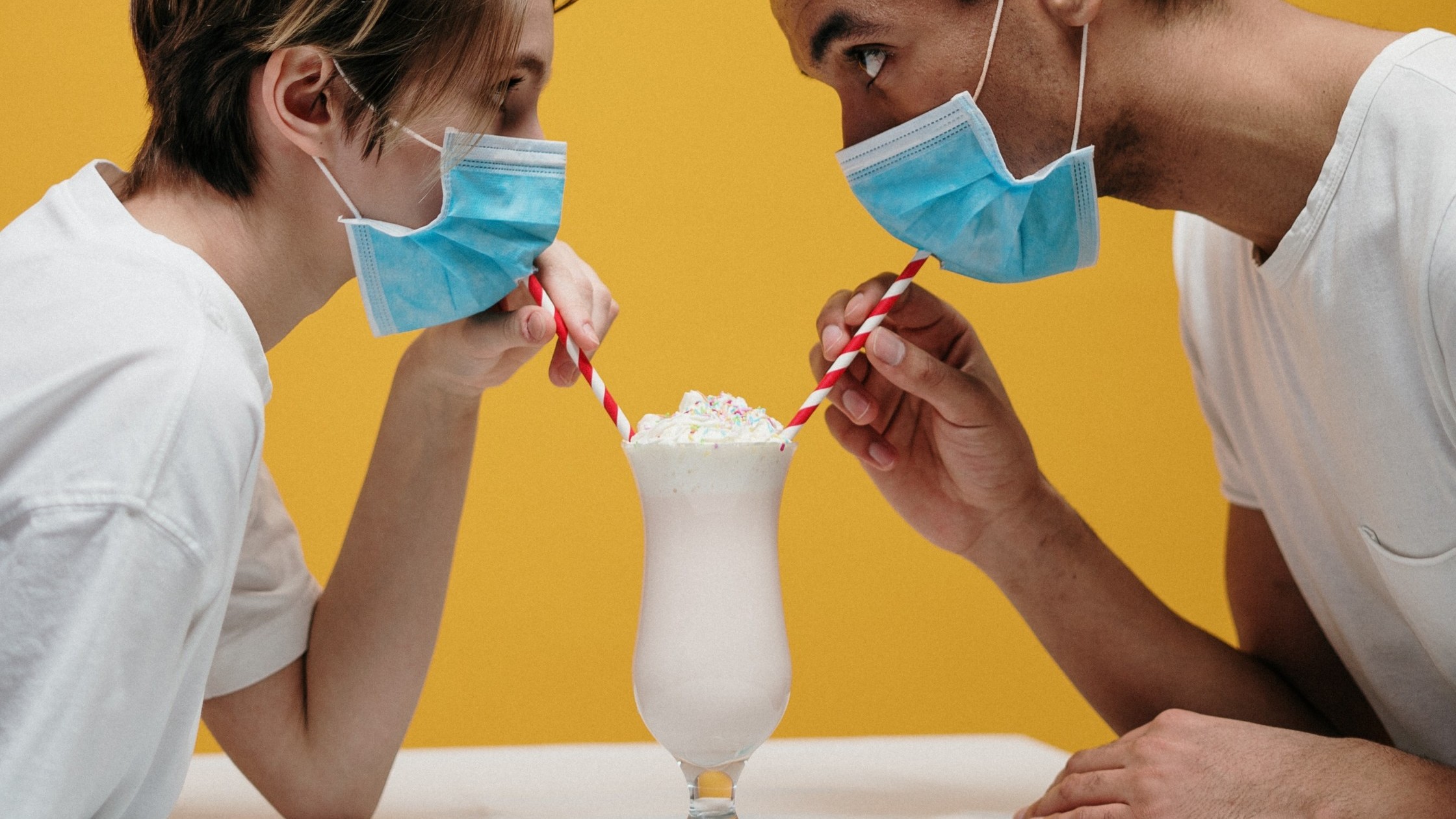 Couple eating together, despite wearing face masks.