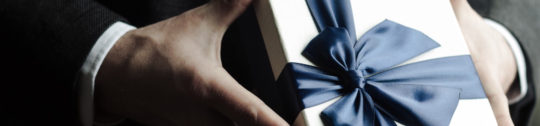 Geschenkbox mit großer Schleife gehalten in Händen 