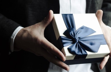 Gift box with large bow held in hands 