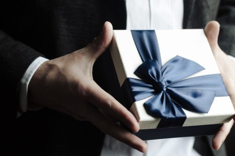 Gift box with large bow held in hands
