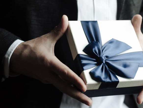 Geschenkbox mit großer Schleife gehalten in Händen