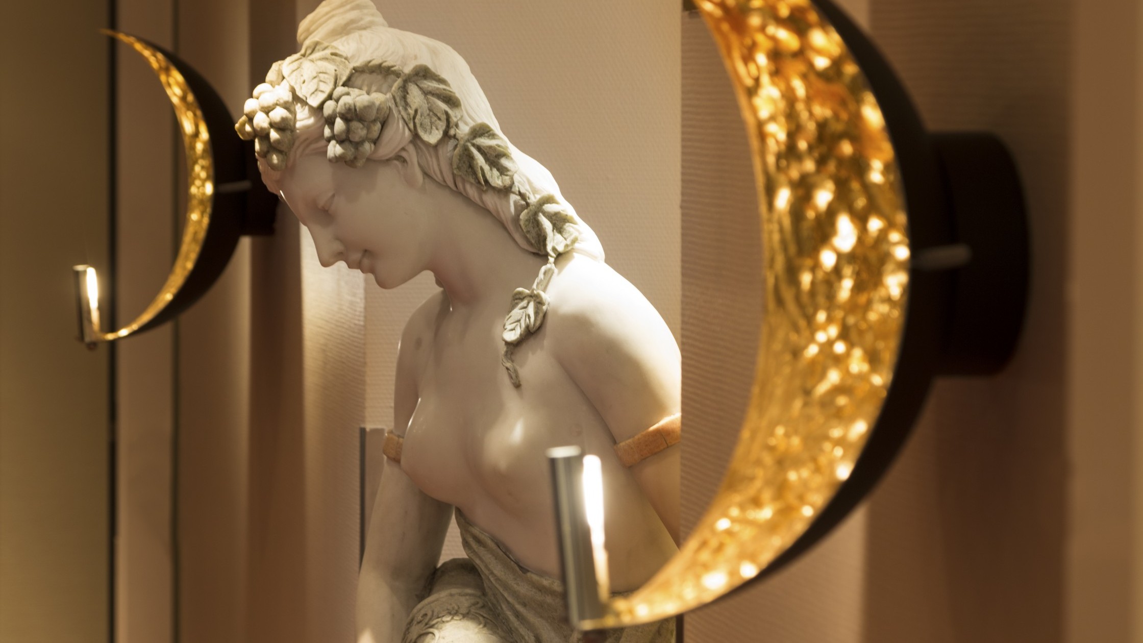 Statue einer Dame mit Früchten im Haar und einem antiken Wassergefäß.