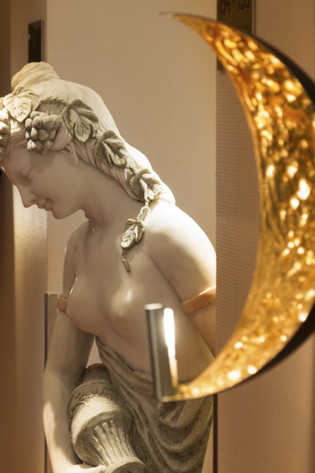 A statue of a lady with fruit in her hair and an antique water vessel.