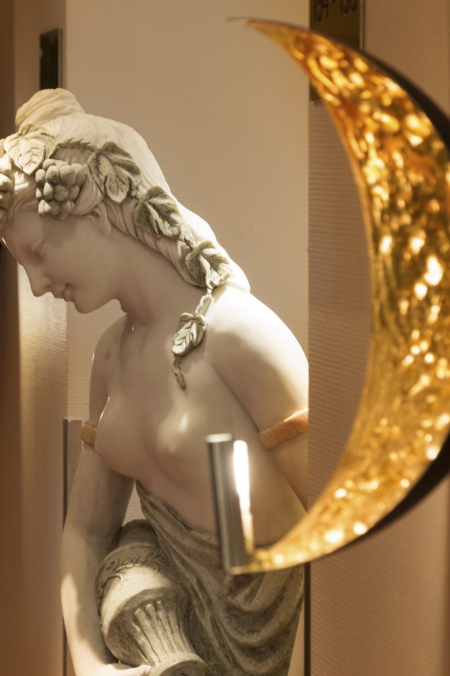 Statue einer Dame mit Früchten im Haar und einem antiken Wassergefäß.