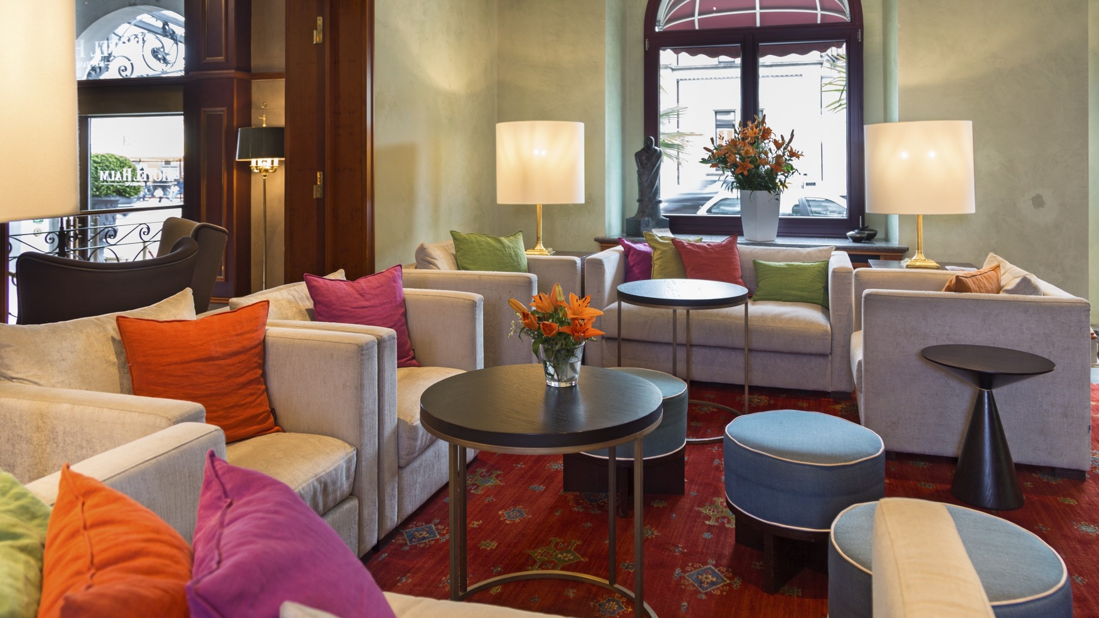 Cozy lounge with sofas by the window facing the sunny south side with fresh flowers.