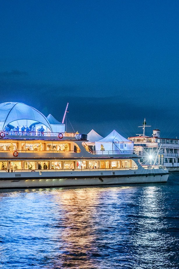 A festively decorated boat serving as an IceBar at the Christmas market in Konstanz, surrounded by lights and visitors.