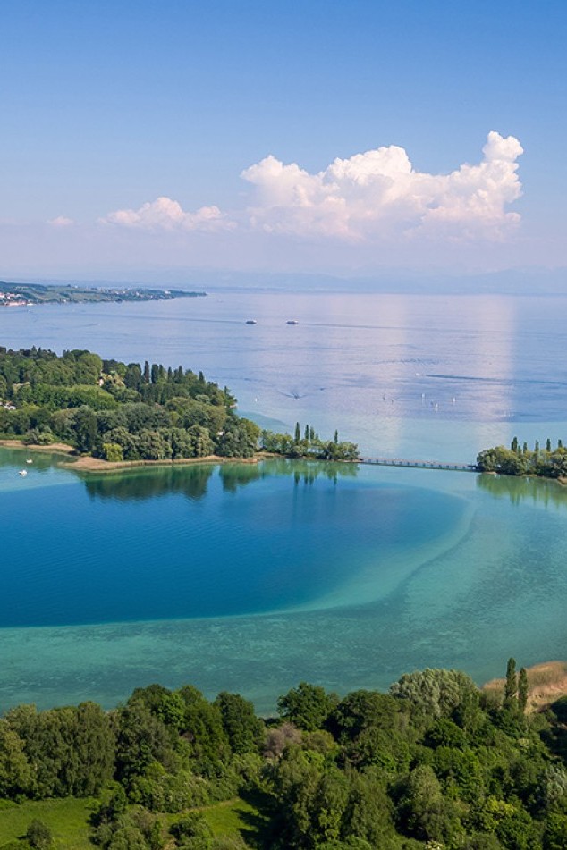Luftbild der Insel Mainau im Bodensee mit üppiger Blumenpracht und dem barocken Schloss im Zentrum.