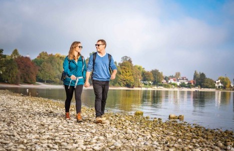  Two couples hiking together along Lake Constance near Konstanz on a sunny day.