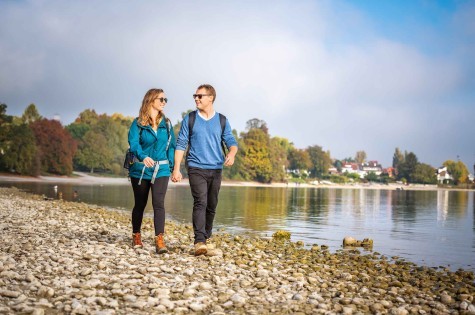 Zwei Paare wandern gemeinsam entlang des Bodensees bei Konstanz an einem sonnigen Tag.