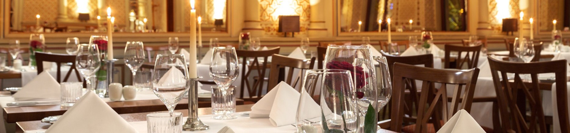  Tables set with red roses and candles in the festive Moorish hall, with a view of the gigantic mirrors and the wonderful wall decorations.