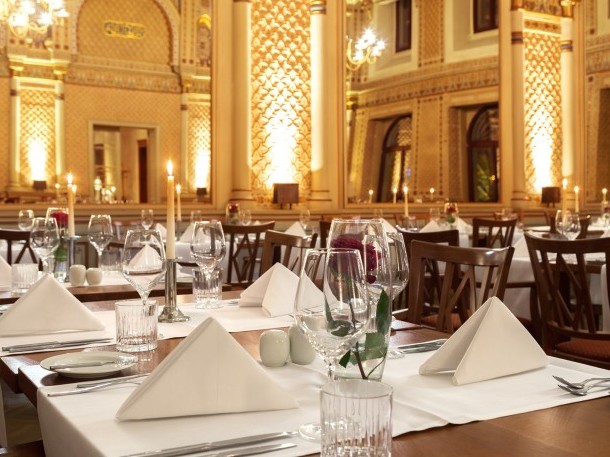 Tables set with red roses and candles in the festive Moorish hall, with a view of the gigantic mirrors and the wonderful wall decorations.