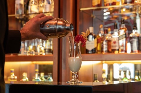 Frisch zubereitete Pina Colada wird in der Bar aus dem Shaker in ein Cockailglas gegossen.