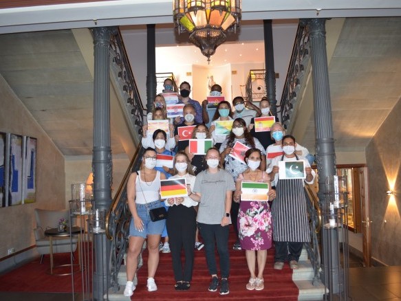 Unsere Mitarbeiter stehen auf der Treppe des Hotel Halm, jeder hält die Flagge seines Herkunftslandes.